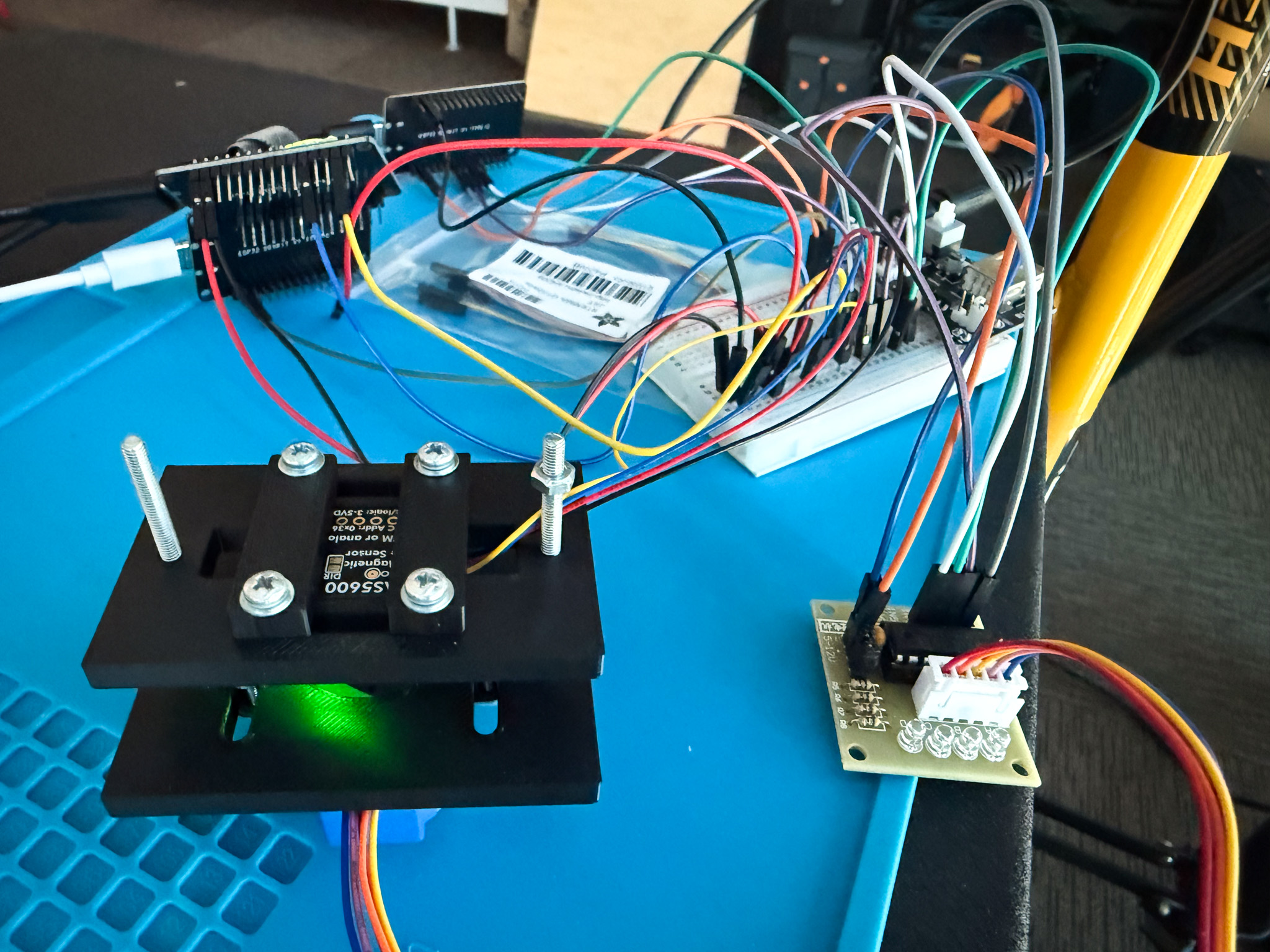 The bench prototype: an AS5600 magnetic sensor in a 3D-printed mount, wired through a breadboard to ESP32 boards and a stepper motor driver